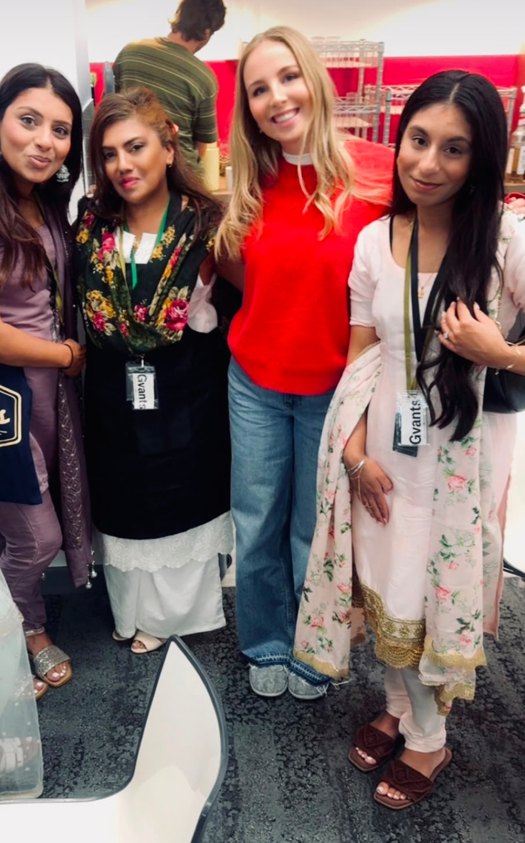 Four colleagues wearing Gvants passes and traditional South Asian outfits at an indoor office event.